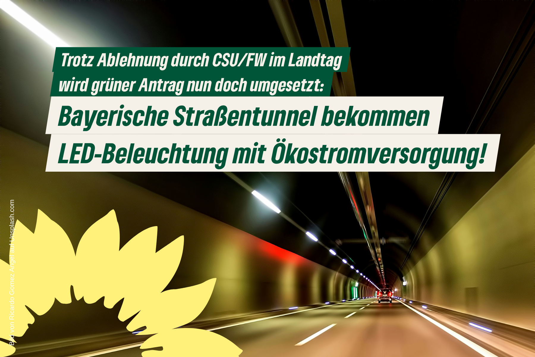 Blick entlang Fahrbahn in beleuchteter Straßentunnel-Röhre mit Sonnenblumenlogo und Text: Nach Ablehnung durch CSU/FW wird unser grüner Antrag nun doch umgesetzt und Straßentunnel bekommen LED-Beleuchtung und dezentrale Ökostromversorgung!