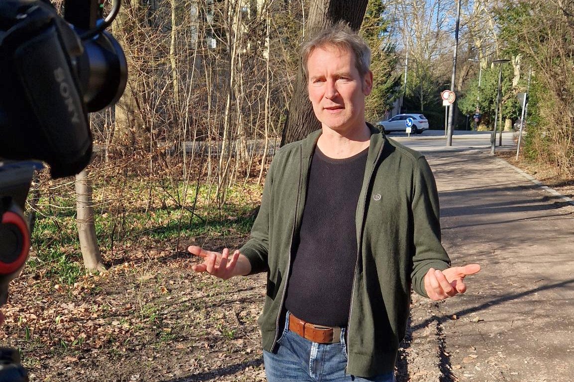 Dr. Markus Büchler, Mdl im Interview im Park hinter dem Bayerischen Landtag gestikulierend und mit Filmkamera im Anschnitt.