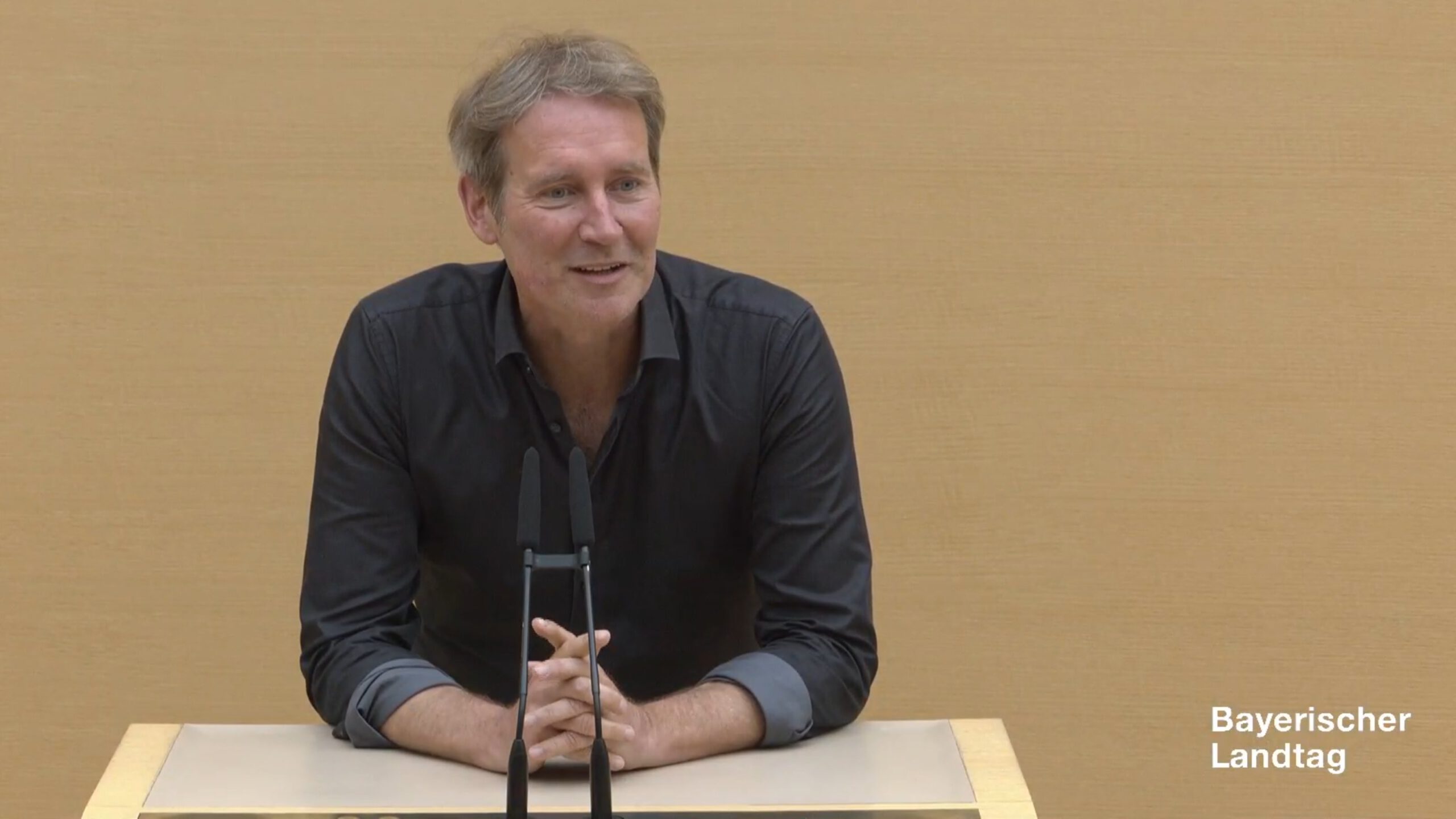 Dr. Markus Büchler in schwarzem Hemd am Redepult im Bayerischen Landtag.