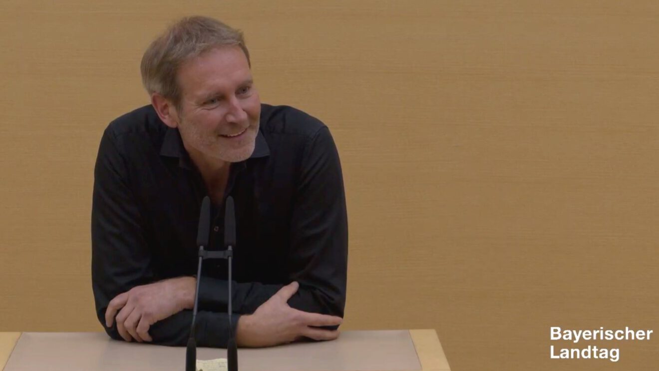 Markus Büchler in schwarzem Hemd am Redepult des Plenarsaals.