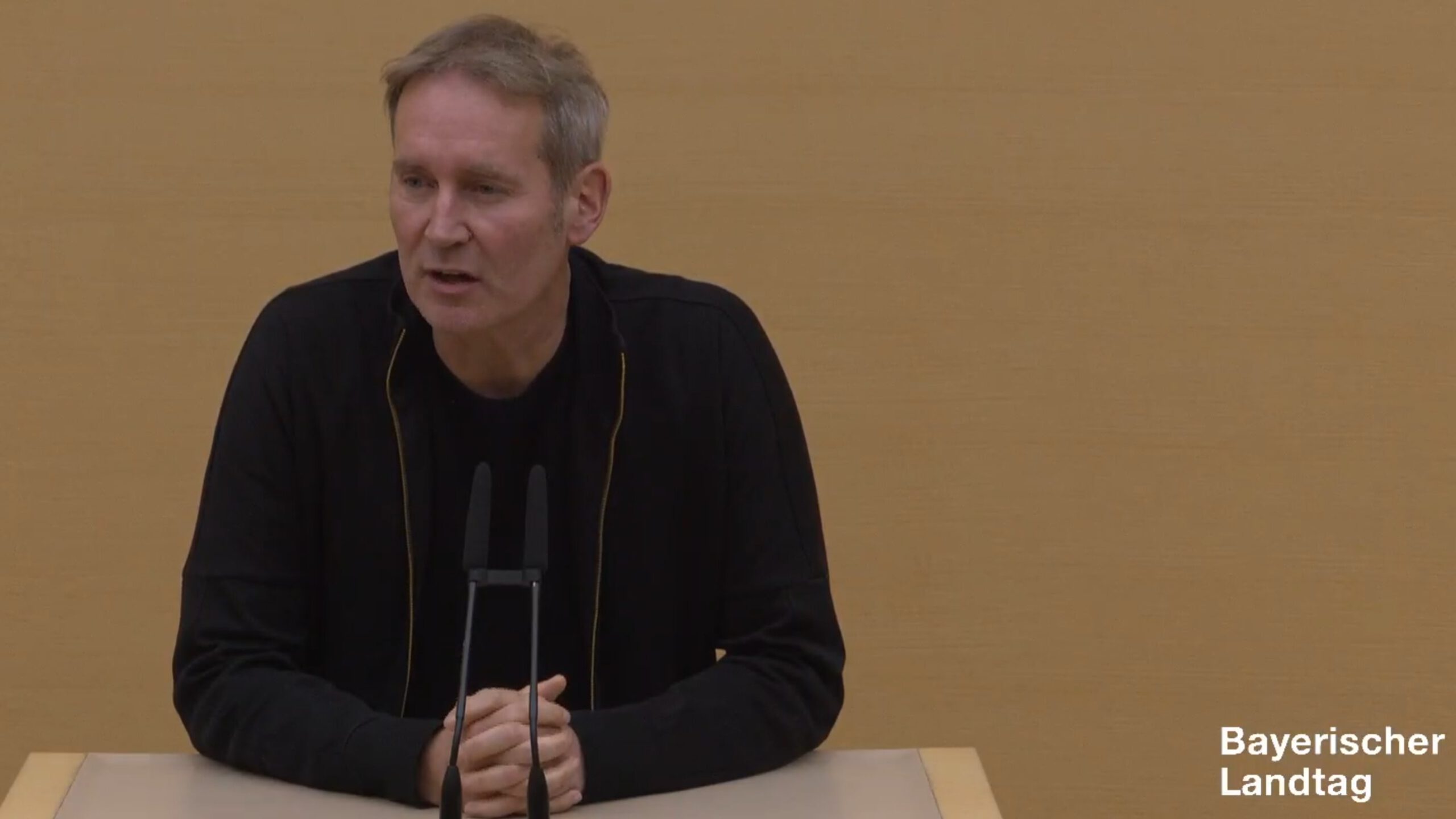 Markus Büchler in schwarzem Hemd am Redepult des Plenarsaals.