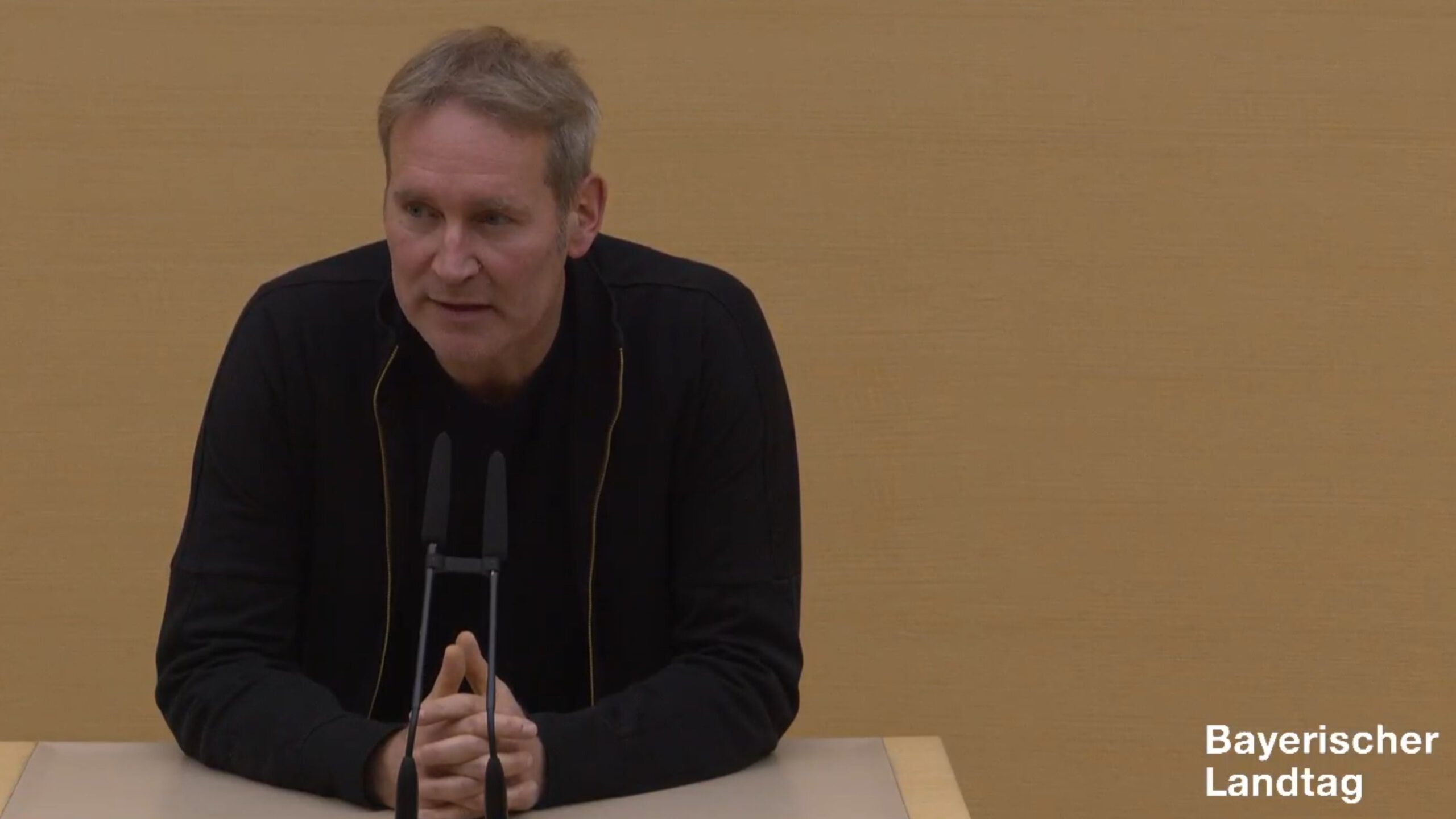Markus Büchler in schwarzem Hemd am Redepult des Plenarsaals.